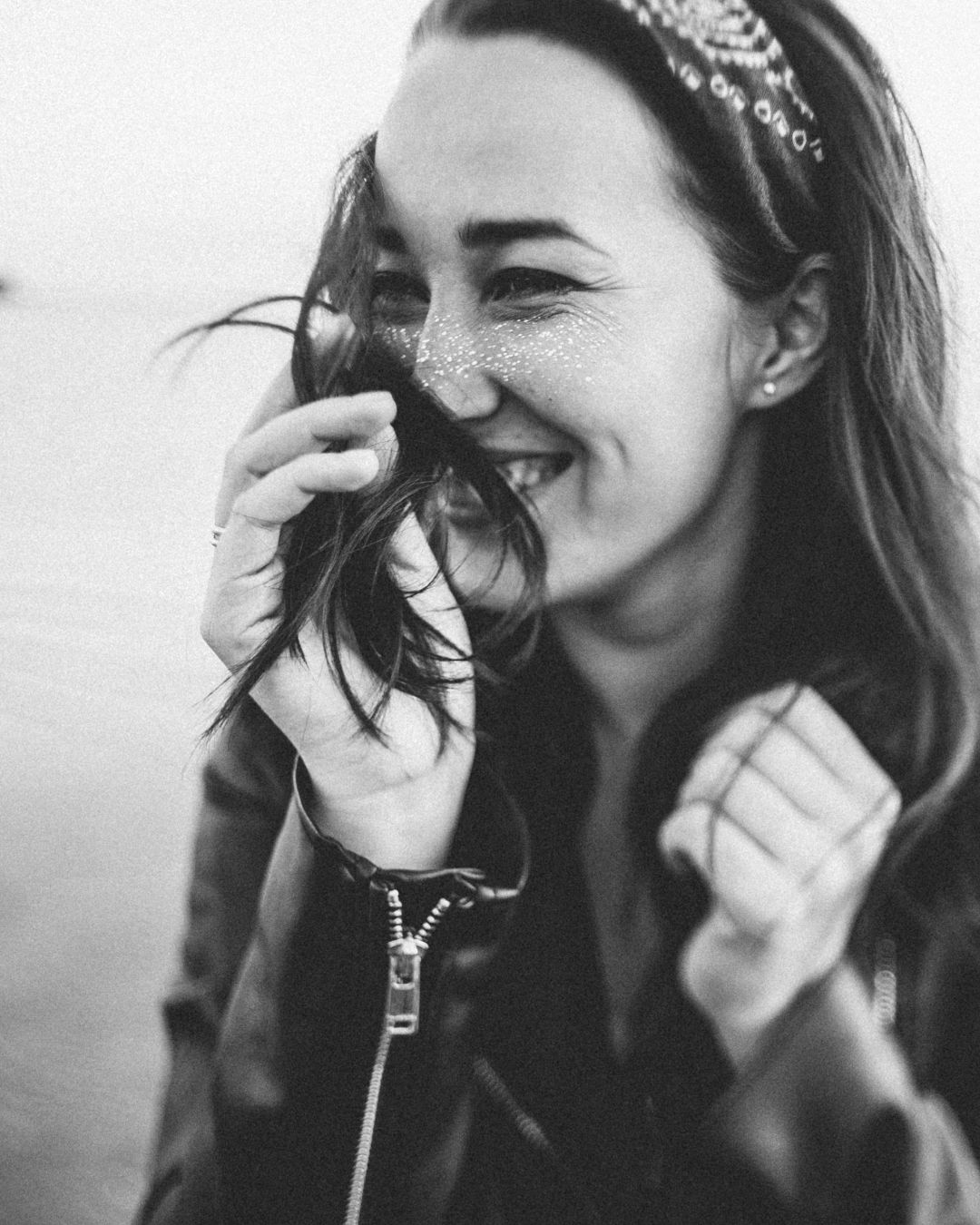Woman smilling and brushing her hair on her face
