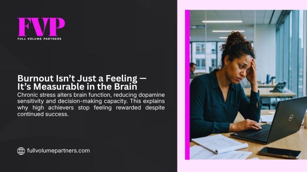 Exhausted woman holding her head at a work desk, illustrating how burnout isn't just a feeling but is measurably linked to reduced dopamine and brain function.