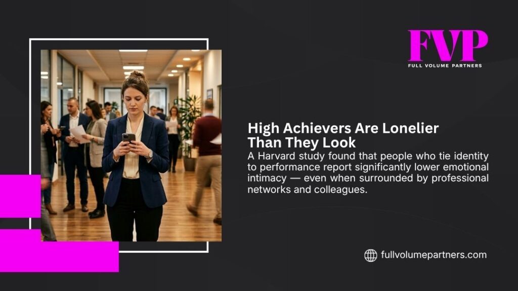 Lone professional woman on phone amid busy office crowd, depicting how high achievers are lonelier than they look despite social surroundings.